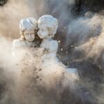 two white concrete statues covered by dust